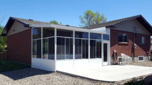 White aluminum sunroom with high ceilings, glass walls, concrete patio