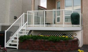Glass railings around raised deck and stairs with white picket railings.