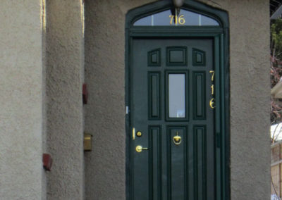 A green door on a stucco house with a little window above the door Saskatoon Pacific Home Product